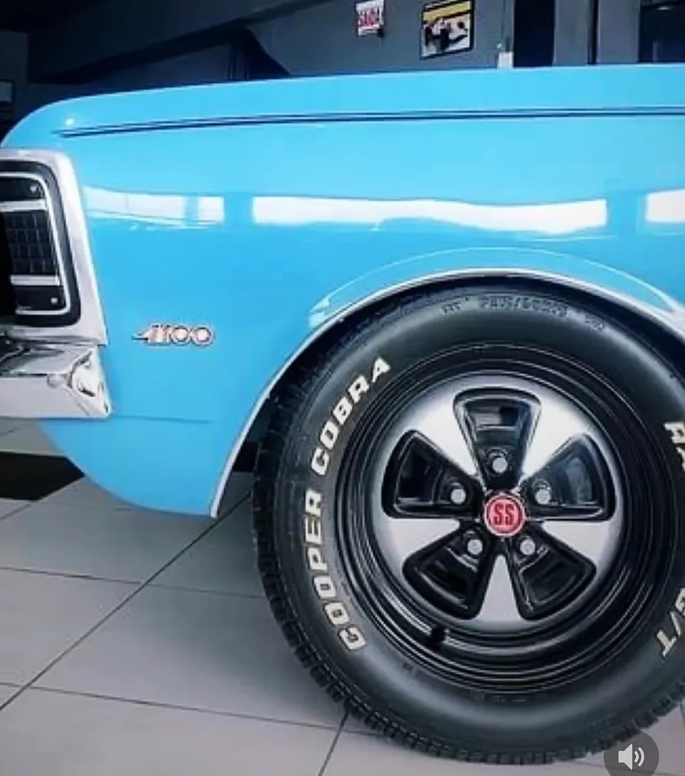Carro clássico azul com roda em preto e pneu de faixa branca