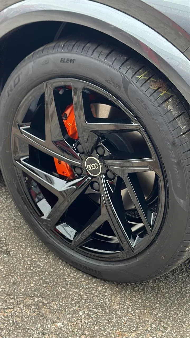 Roda Audi preta brilhante com a pinça de freio laranja aparecendo entre os raios